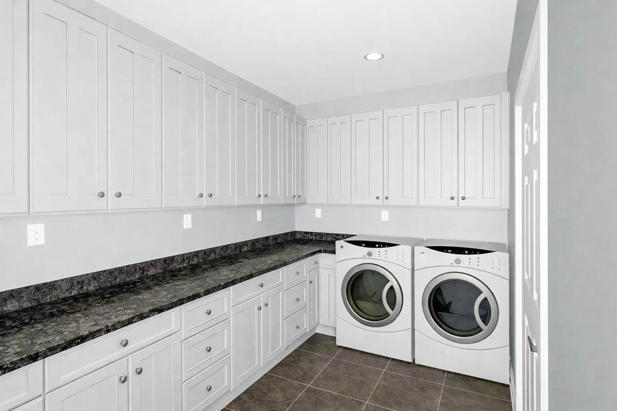 Laundry room with white cabinets, dark granite countertops, two front-load washers, and tiled flooring.