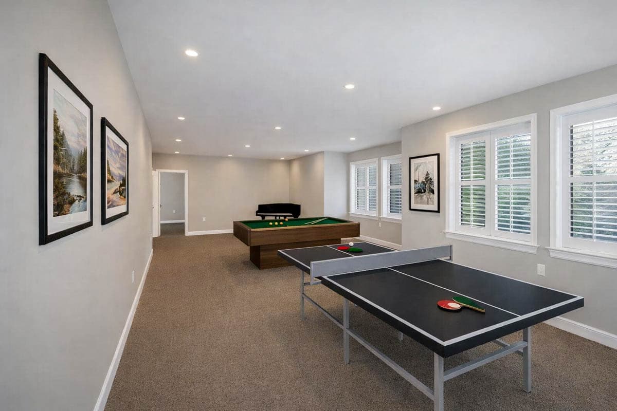 Recreation room interior with ping pong table, pool table, and plantation shutters on windows.