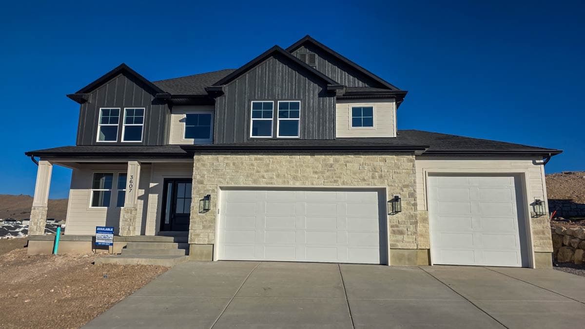 House plan exterior: Two-story home with stone veneer, vertical siding, front-facing gables, and a two-car attached garage.