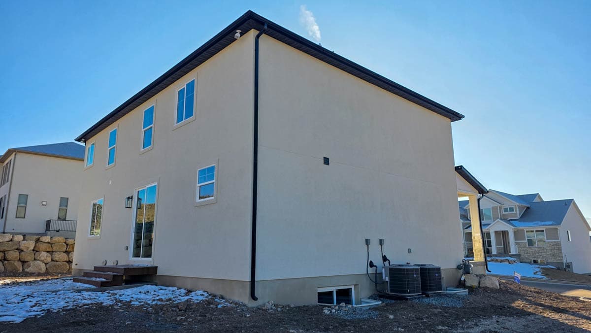 Two-story Modern Farmhouse exterior with stucco siding, gabled roof, multiple windows, and sliding glass doors.