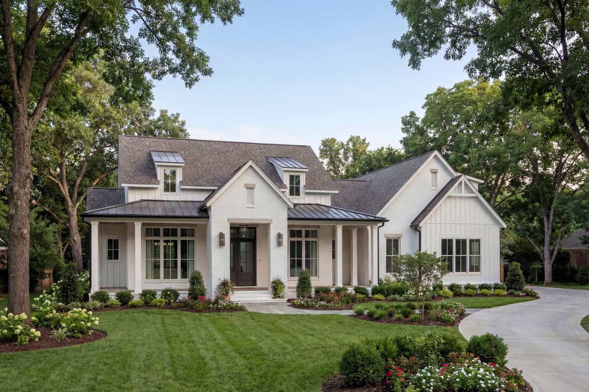 House plan exterior. Two-story Modern Farmhouse with gables, porch with columns, and dormers. Features include a dark metal roof and brick facade.