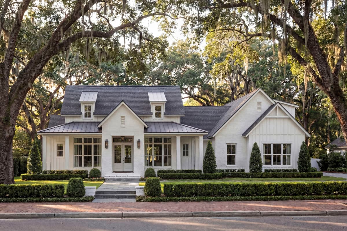 House plan exterior. Modern Farmhouse style, one-story. Features include a front porch with metal roof, multiple dormers, and gabled rooflines.