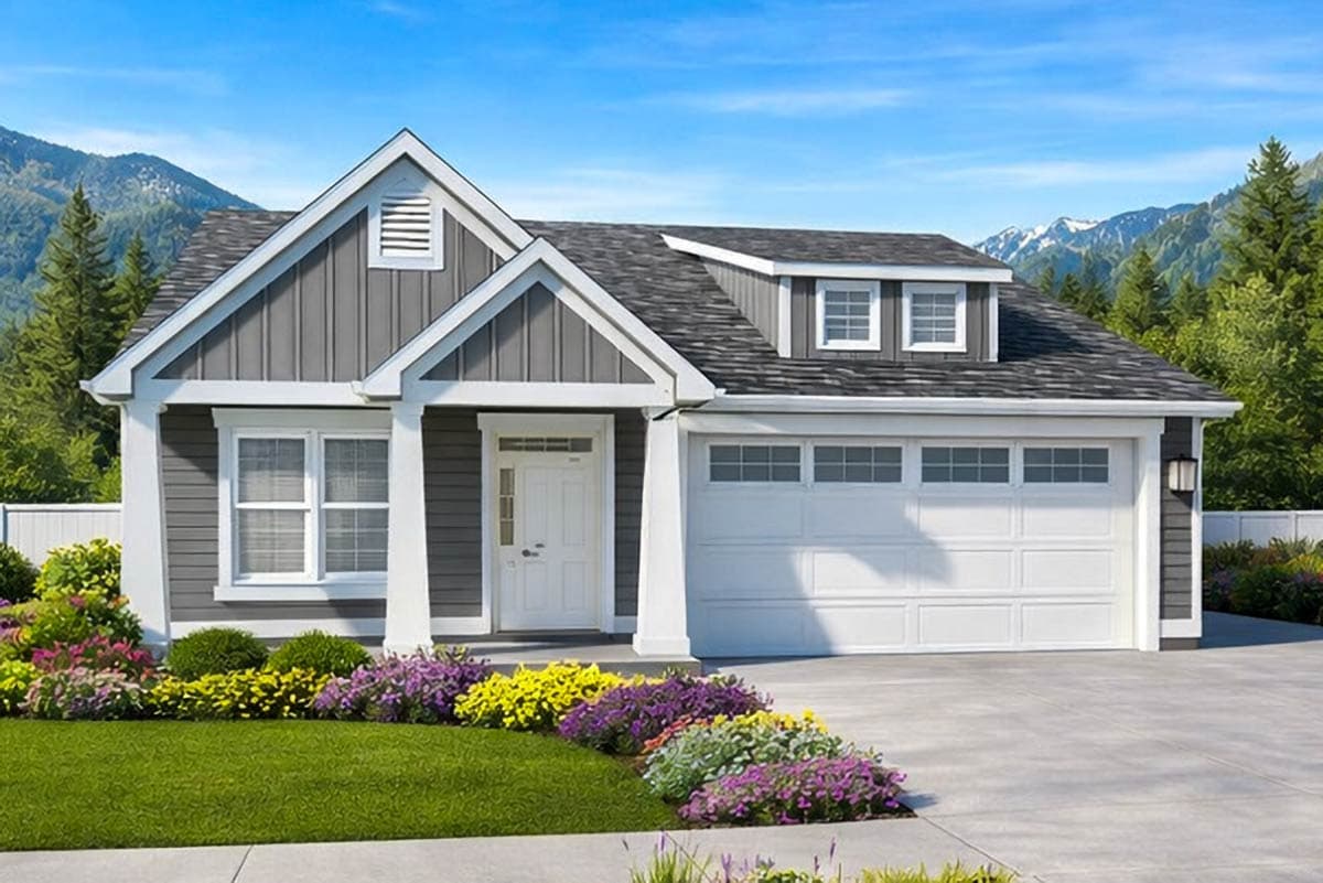 A gray house with white trim, a garage door, and a front lawn. Purple, yellow, and green flowers are in front. Mountains are in the background.