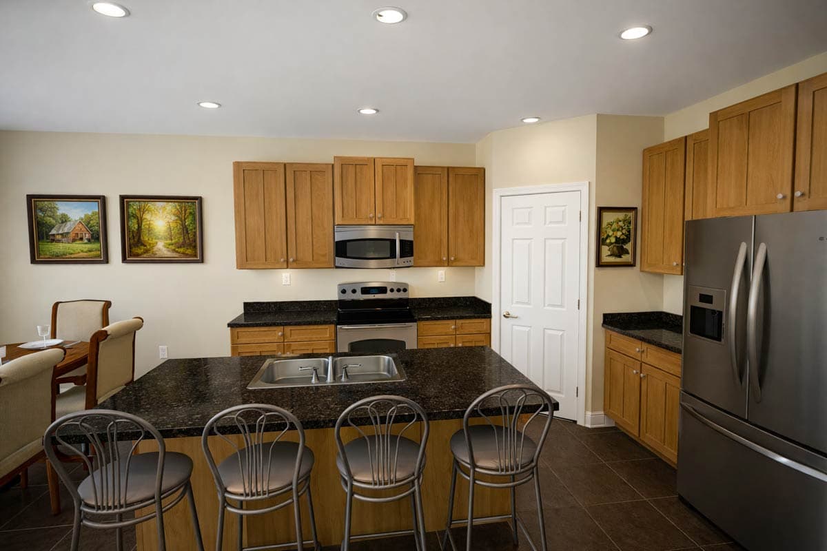 Kitchen with wood cabinetry, granite countertops, island with sink, stainless steel appliances, and a dining area.