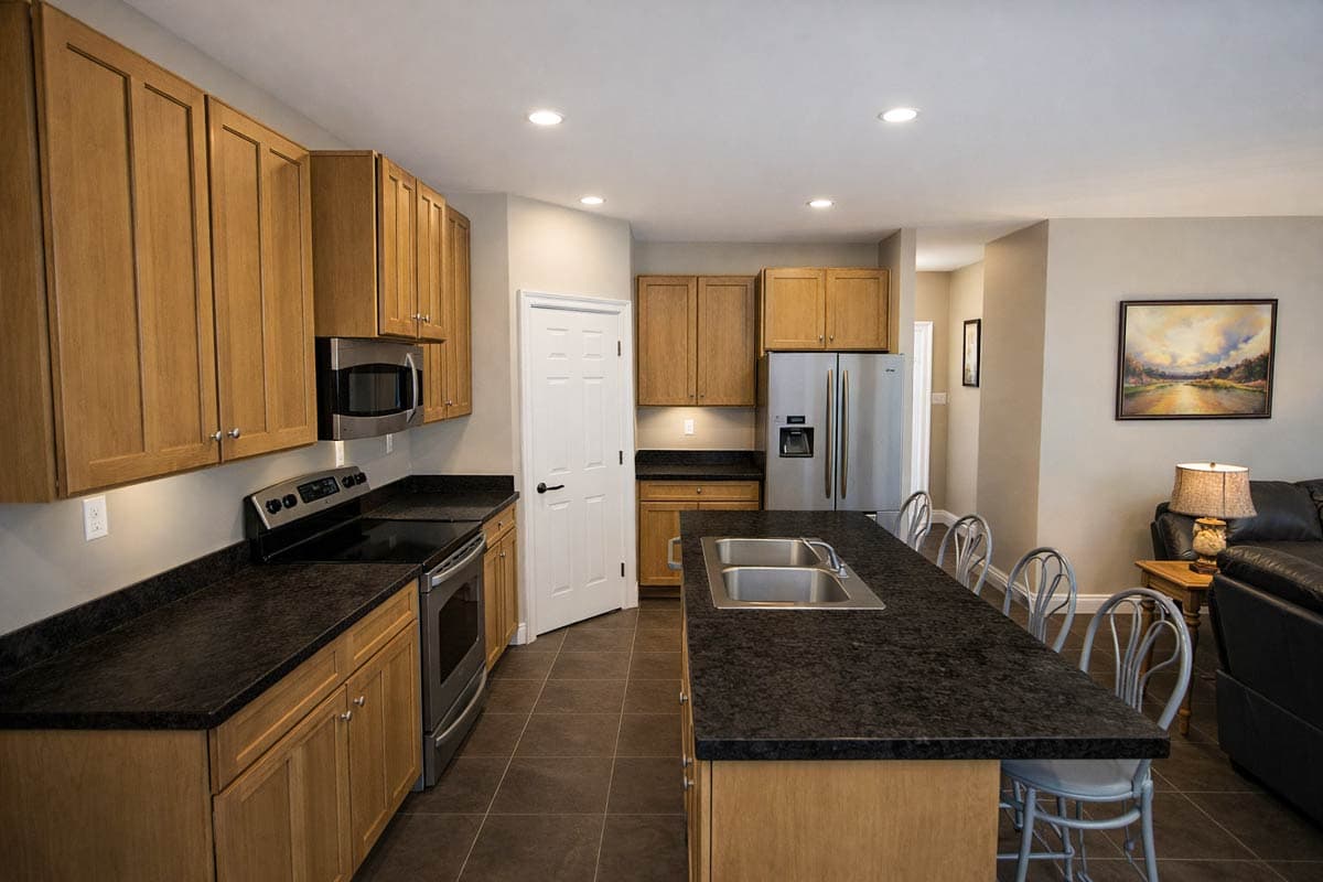 Kitchen featuring wood cabinets, granite countertops, stainless steel appliances, and a large island with a sink.