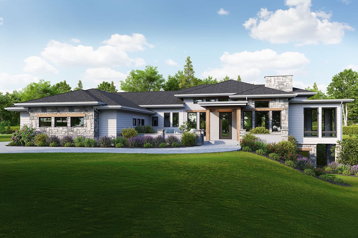 A modern, single-story home with a stone facade, surrounded by lush green lawn and landscaping. The house features a dark roof and large windows.