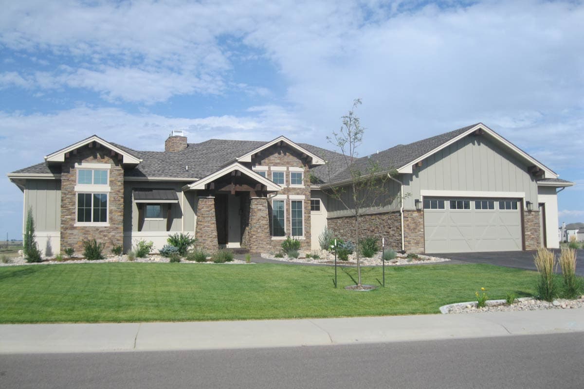 House plan exterior with Craftsman style, stone accents, gables, dormers, covered entry, and three-car garage.