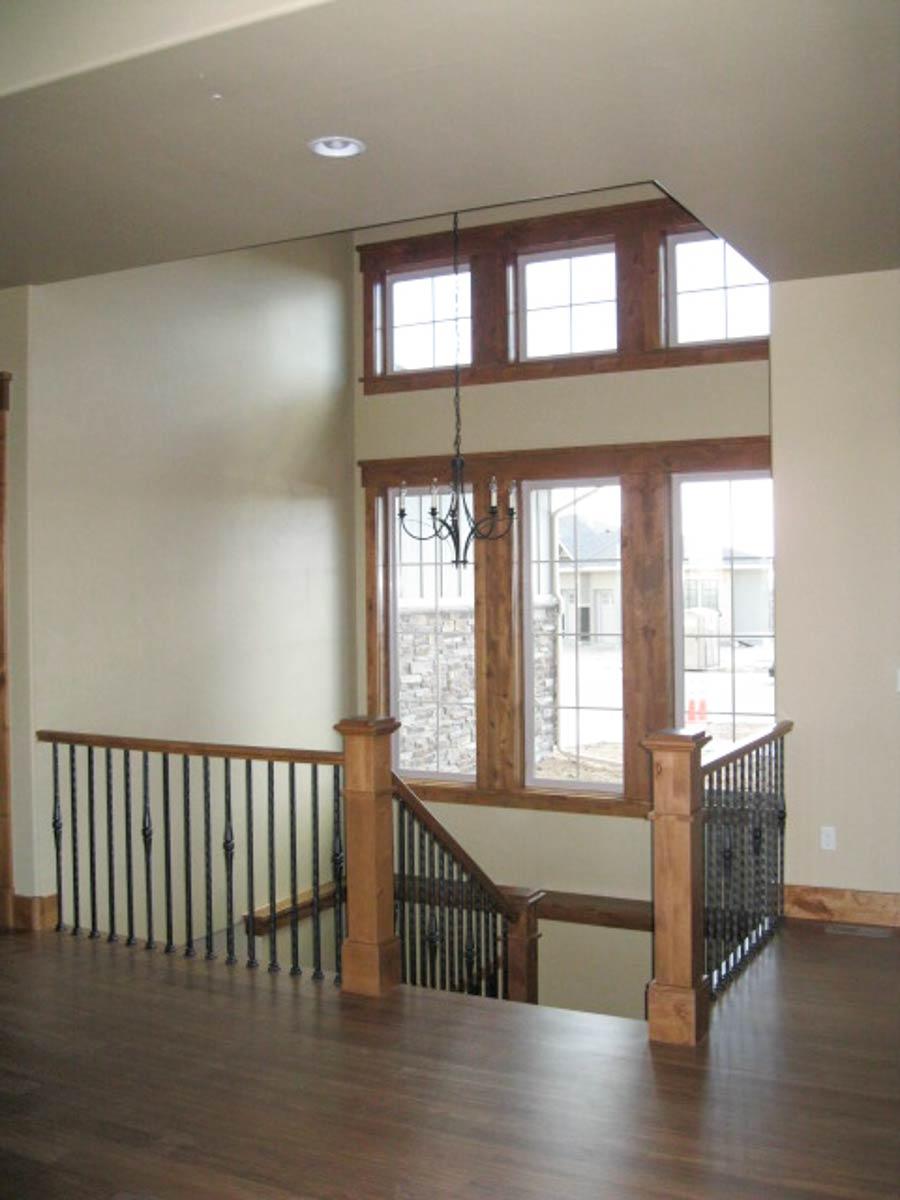 Interior view showing a staircase with wrought iron balusters and wood trim, leading to a landing with multiple windows.
