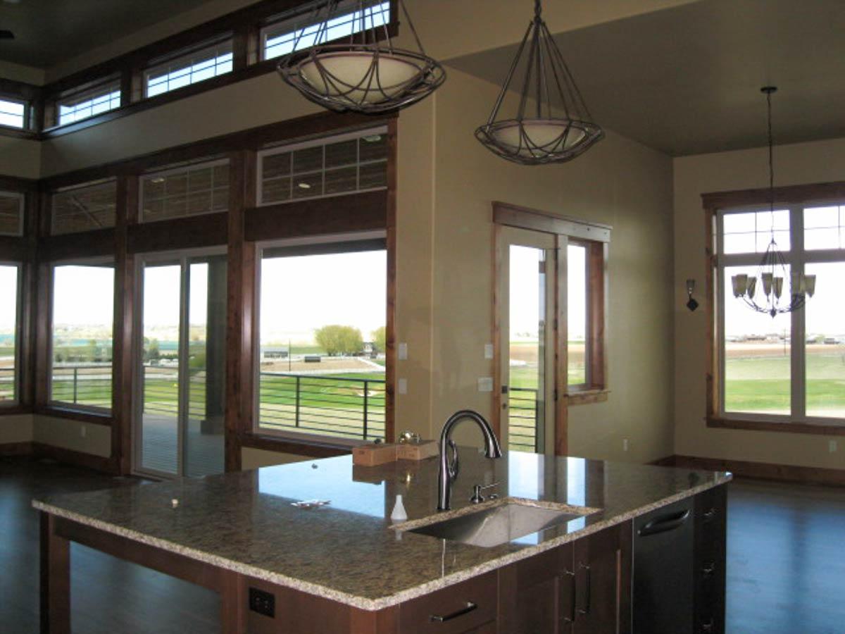 Kitchen island with sink and granite countertop, expansive windows, and dark wood trim throughout.