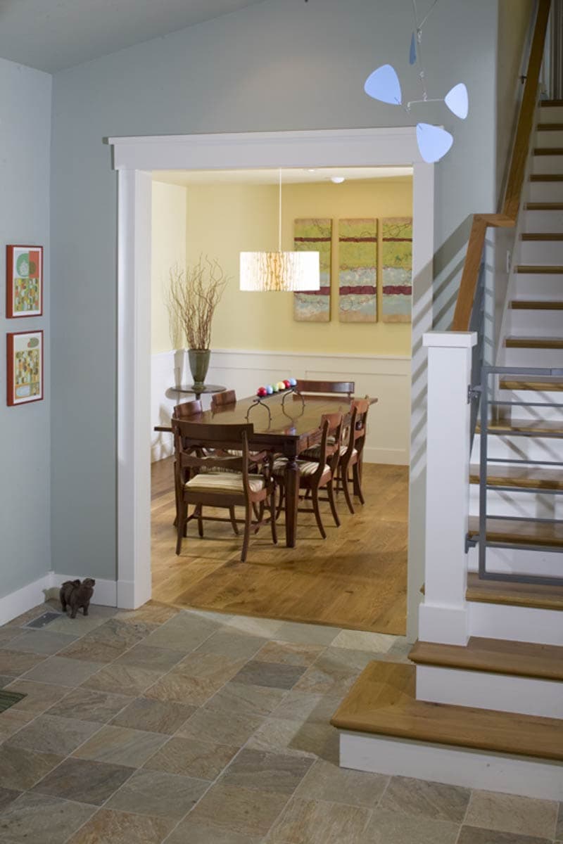 Interior view of a dining room with a wood table and chairs, visible doorway, and a staircase.