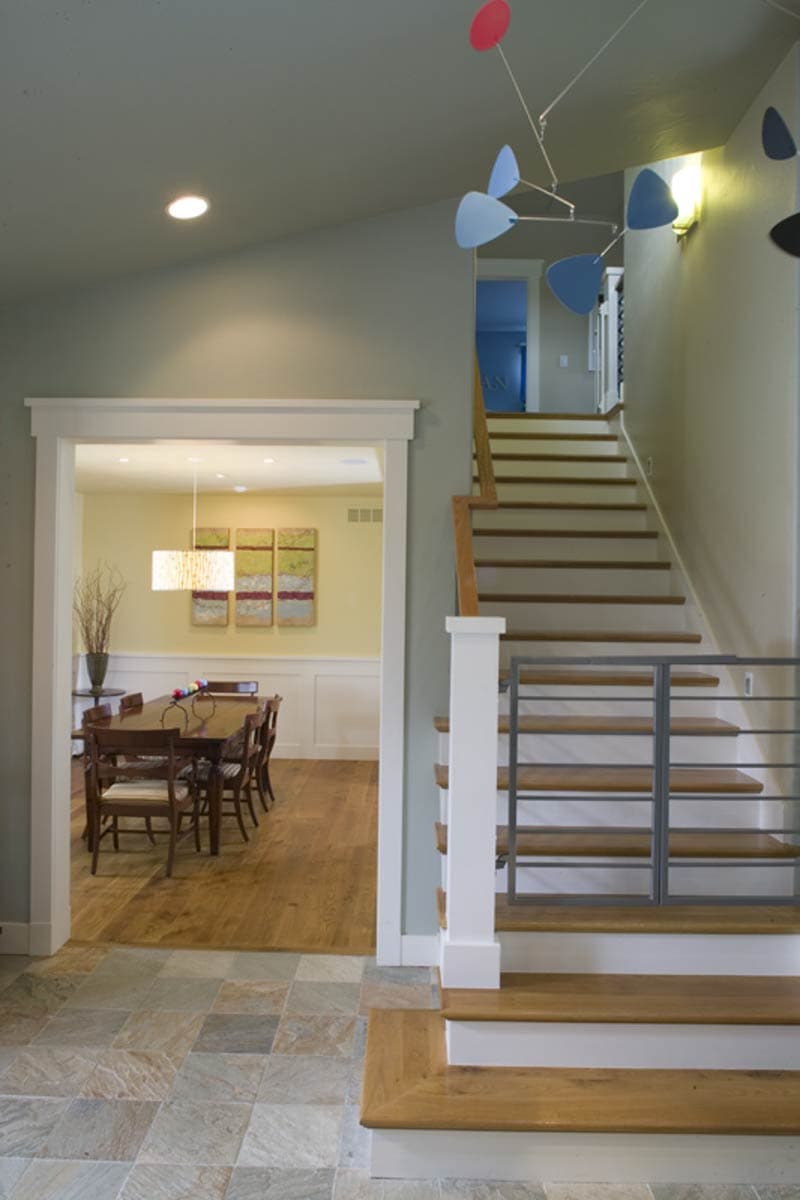 Interior view showing a dining room and a staircase with wooden treads and metal railings, leading to the upper level.