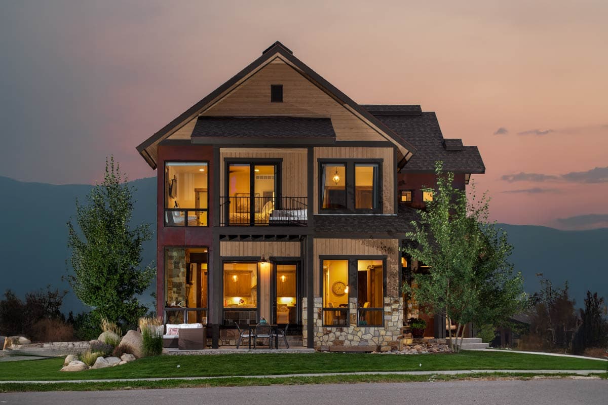Modern house plan exterior with stone accents, multi-level rooflines, a second-story balcony, and large windows.