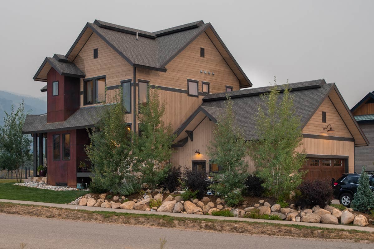 House plan exterior: Modern multi-story home with wood siding, dark trim, gables, and attached garage.