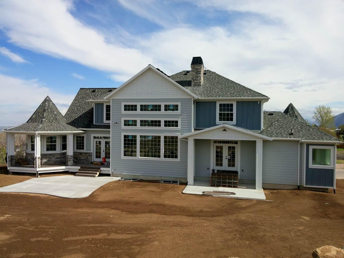 House plan exterior with conical turret porch, stone accents, multiple gables, and a multi-window wall.