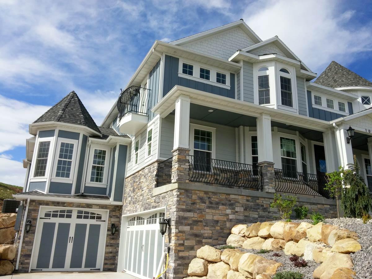 House plan exterior: Two-story residence with multi-level gables, stone facade, prominent porch with columns, and turret.