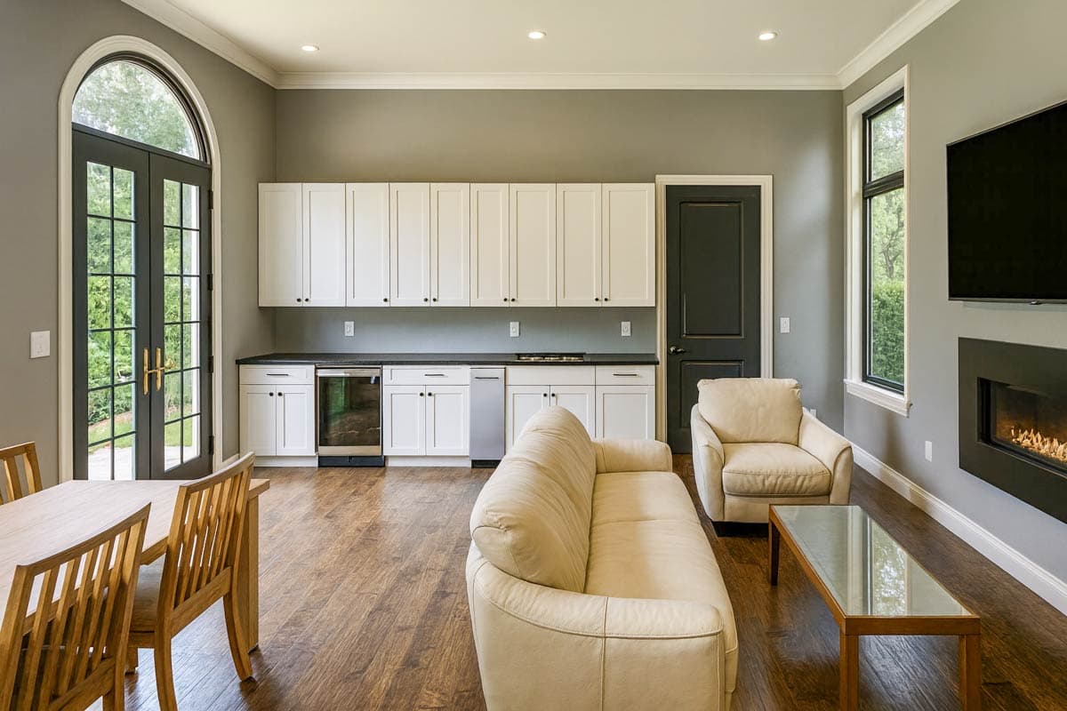Interior view: open living area with kitchenette, sofa, fireplace, and arched French doors.