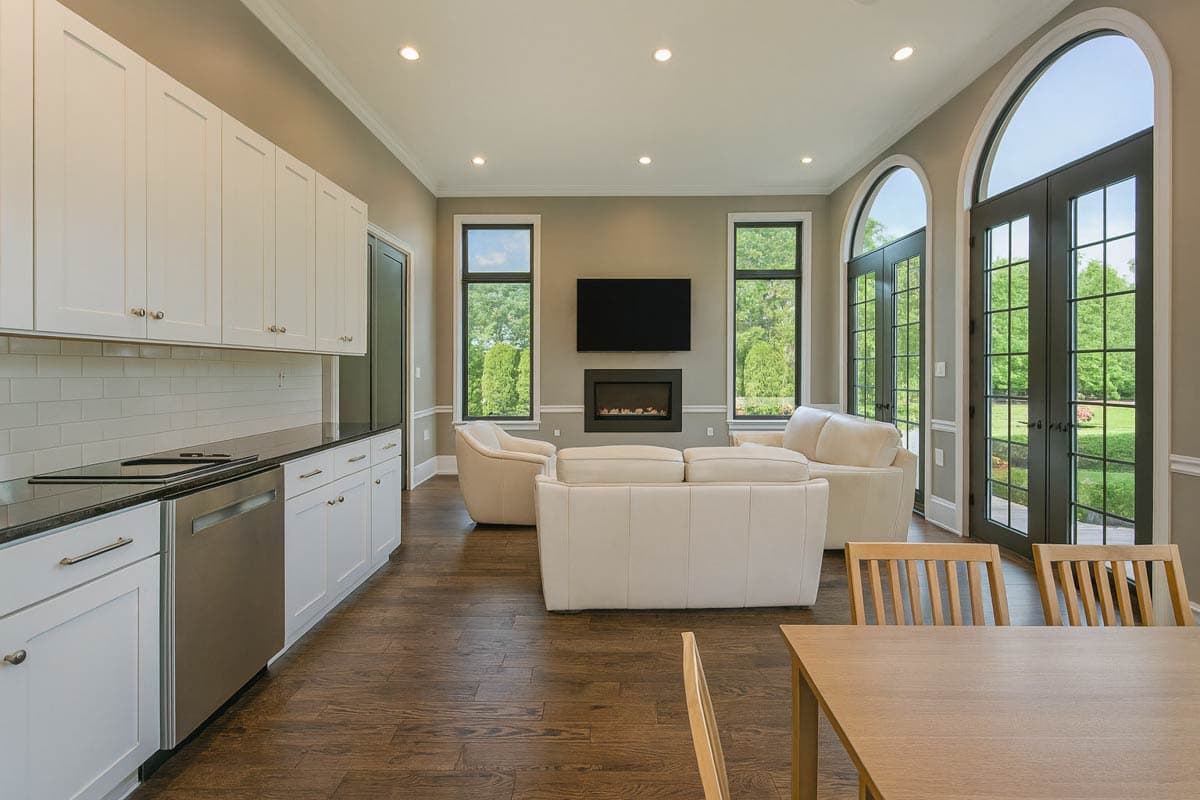 Open concept living area with kitchen island, fireplace, and arched French doors.