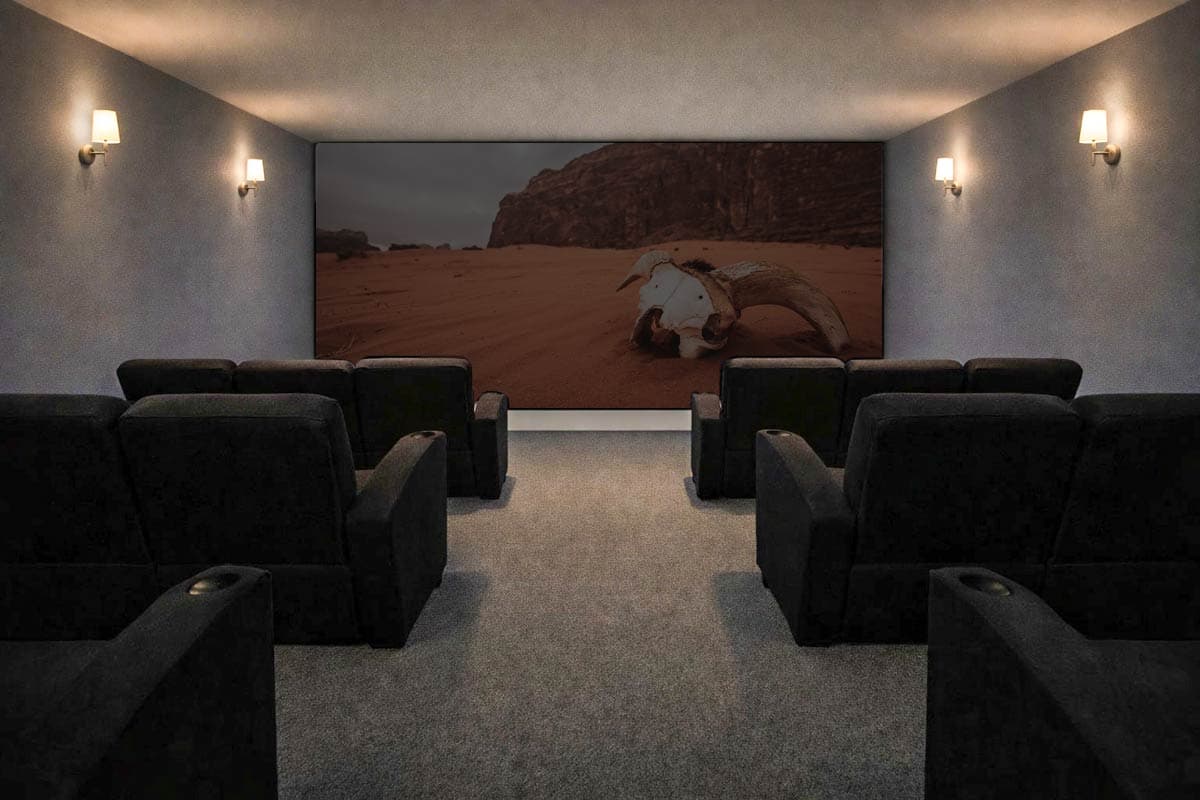 Home theater with multiple rows of black recliners facing a large screen displaying desert landscape art.