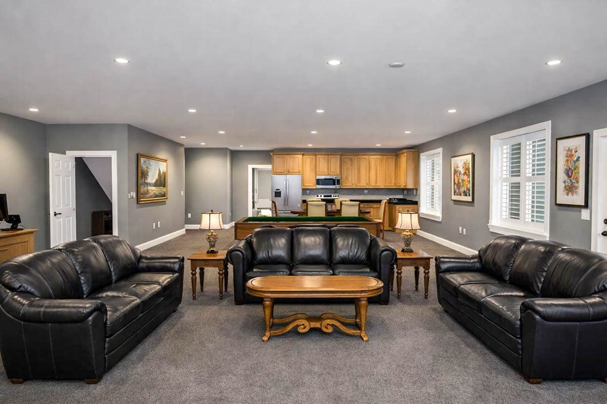 Recreation room with leather sofas, pool table, and full kitchen with wood cabinetry.
