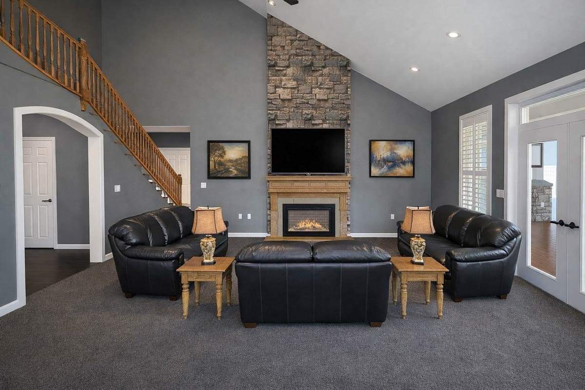 Great room interior with vaulted ceiling, stone fireplace, and wood staircase.