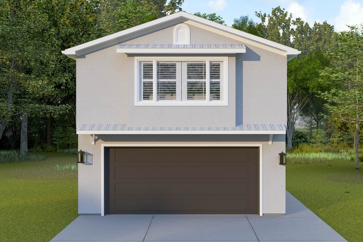 A two-story stucco building with a dark brown garage door, windows with shutters, and a sloped roof. Trees surround the building.
