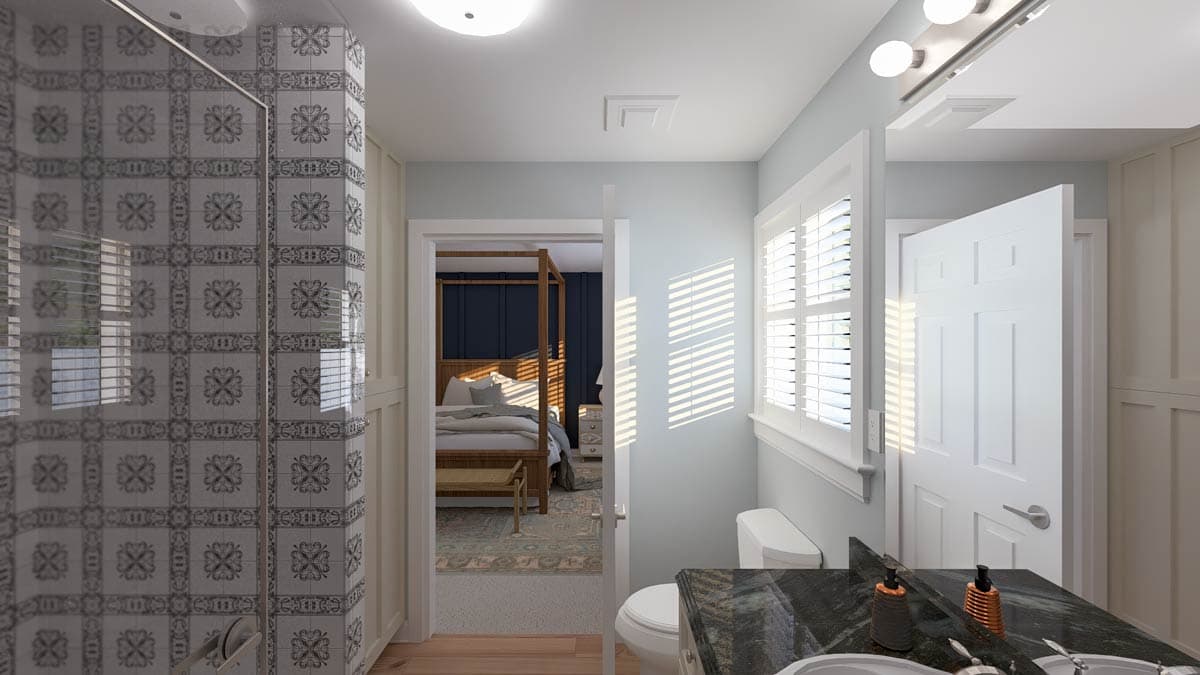 Bathroom with patterned tile shower, vanity, toilet, and view into bedroom with four-poster bed.