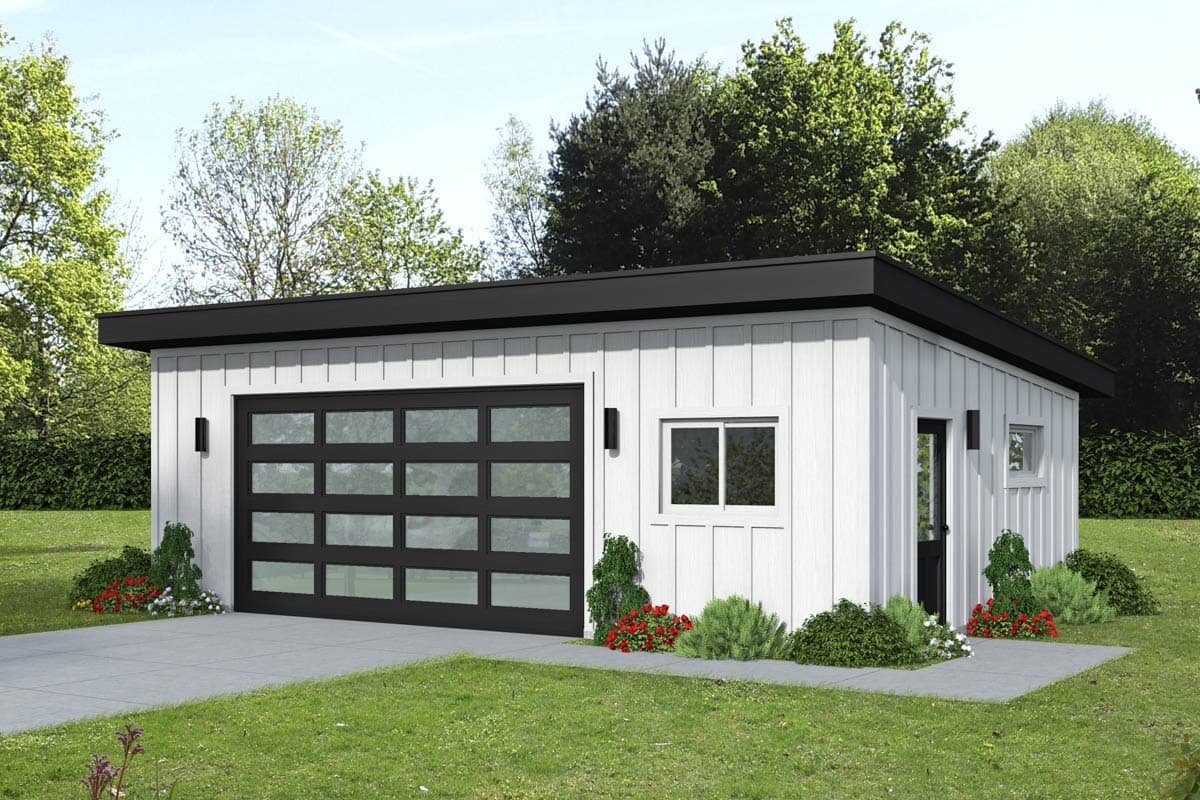 A modern, white garage with a black roof and glass garage door. Landscaping with small shrubs and flowers surrounds the building.