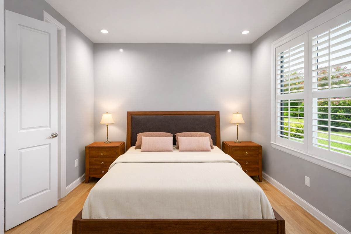 Primary bedroom with queen bed, wood nightstands, recessed lighting, and plantation shutters on window.