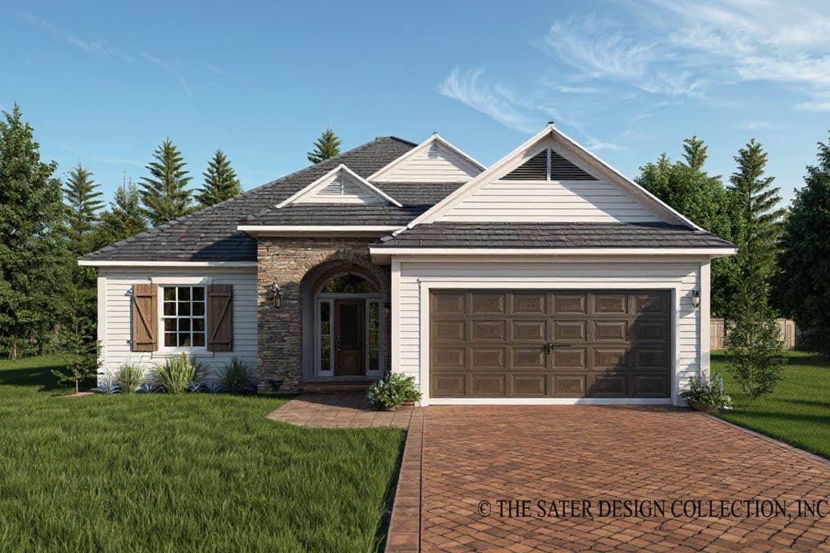 A craftsman-style house with stone accents and a brick driveway. Features include a garage door, gabled roof, and lush green lawn under a blue sky.