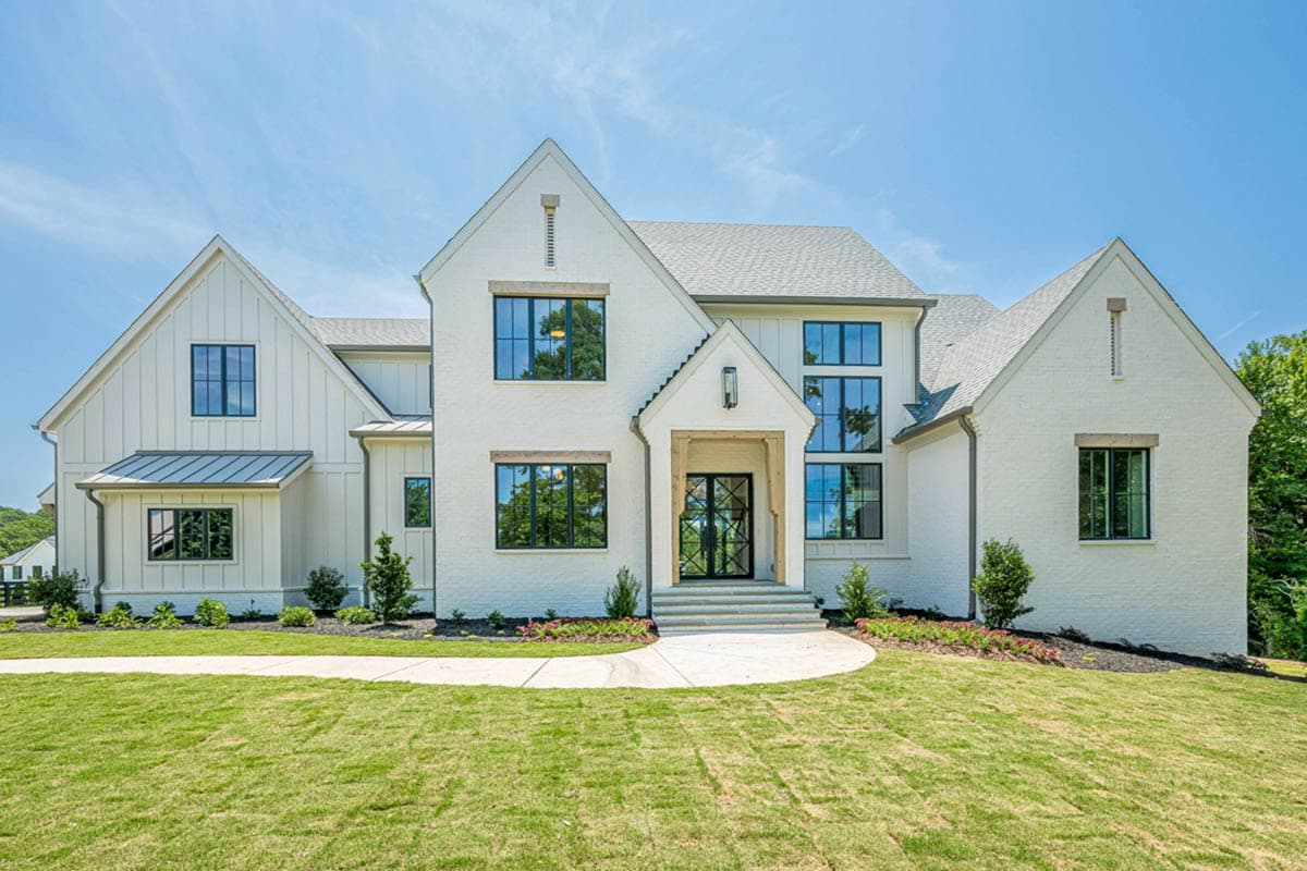 House plan exterior: Modern Farmhouse style, two stories, white brick, board and batten siding, metal roof accents, and prominent gables.