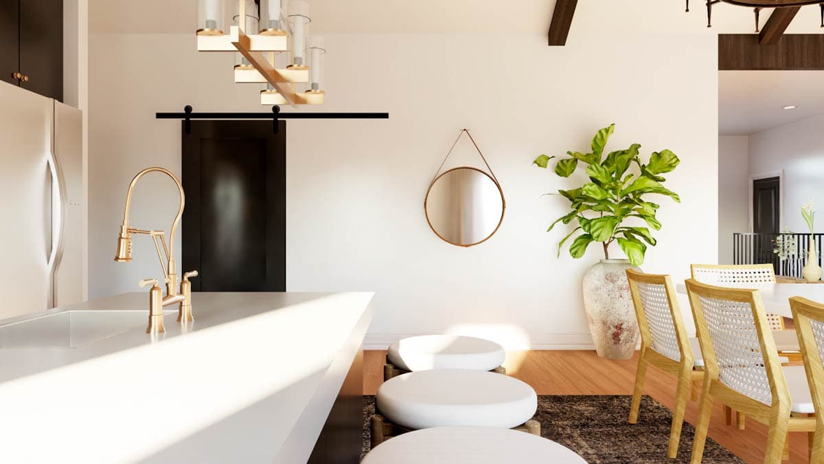 Modern kitchen with island, gold faucet, barn door, and pendant lighting. Dining area with cane-back chairs.