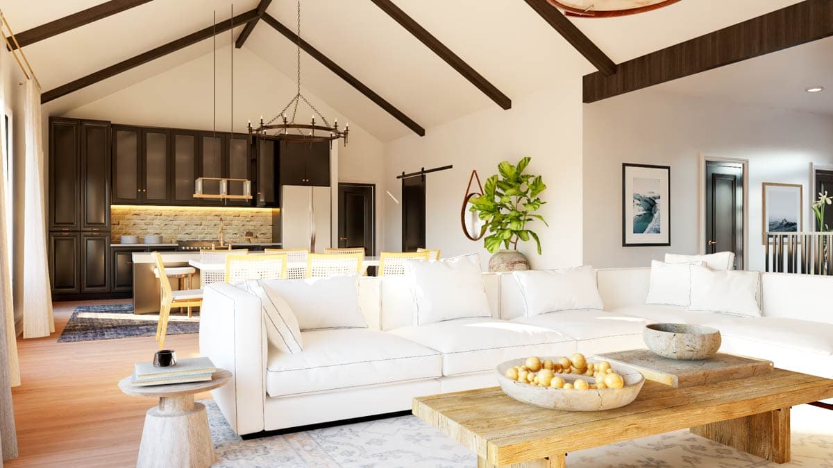 Great room and kitchen with vaulted beamed ceiling, dark cabinetry, island, and white sectional sofa.