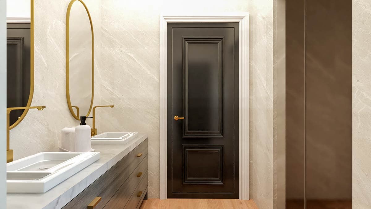 Bathroom vanity with dual sinks and gold faucets, adjacent to a paneled dark door and marble walls.