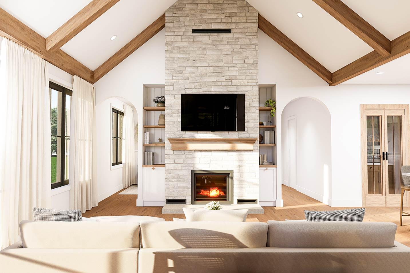 Great room with vaulted ceiling, exposed beams, stone fireplace, built-in shelves, and large windows.