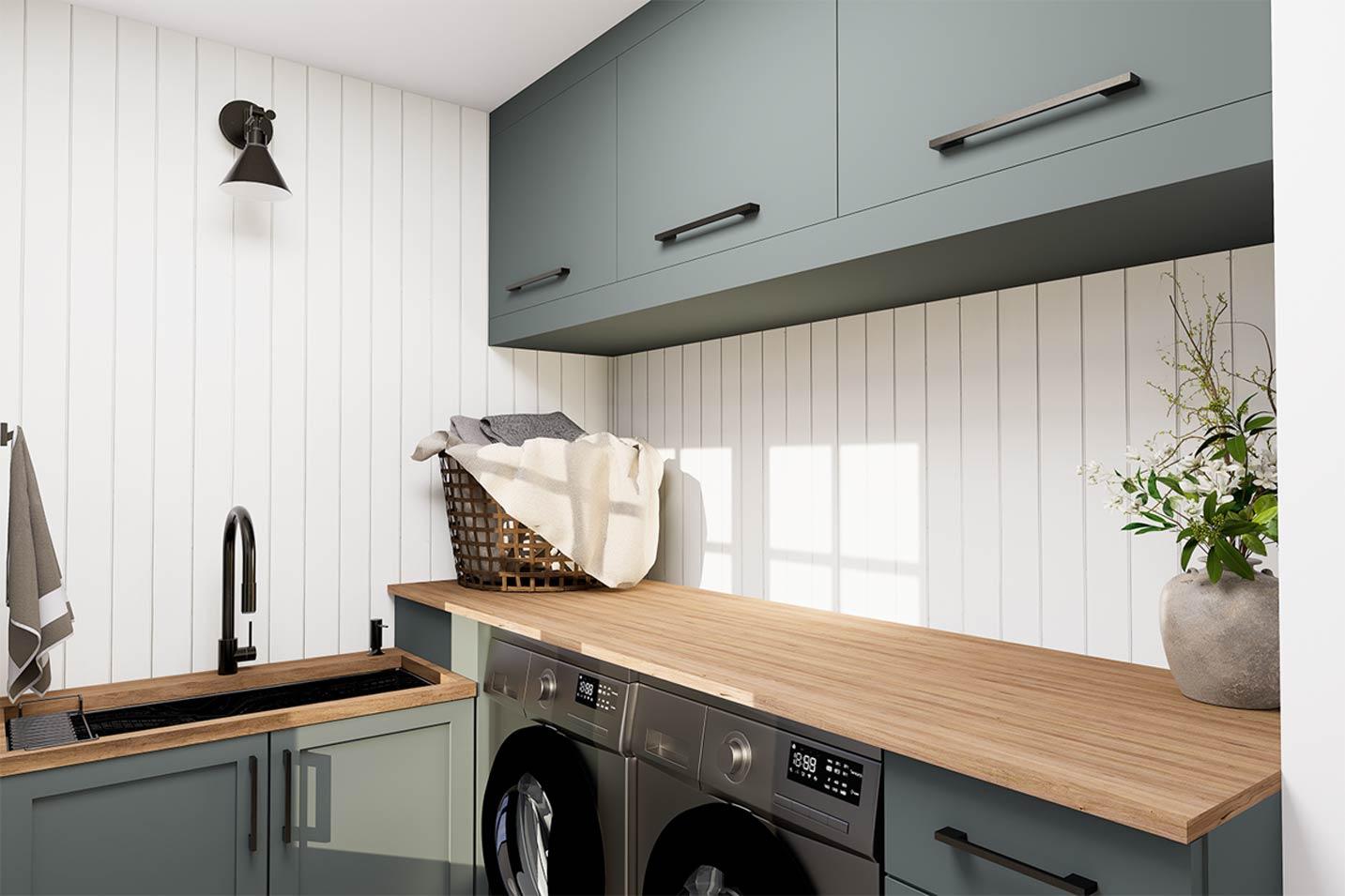 Laundry room interior with sink, washer, dryer, wood countertop, and green cabinetry.