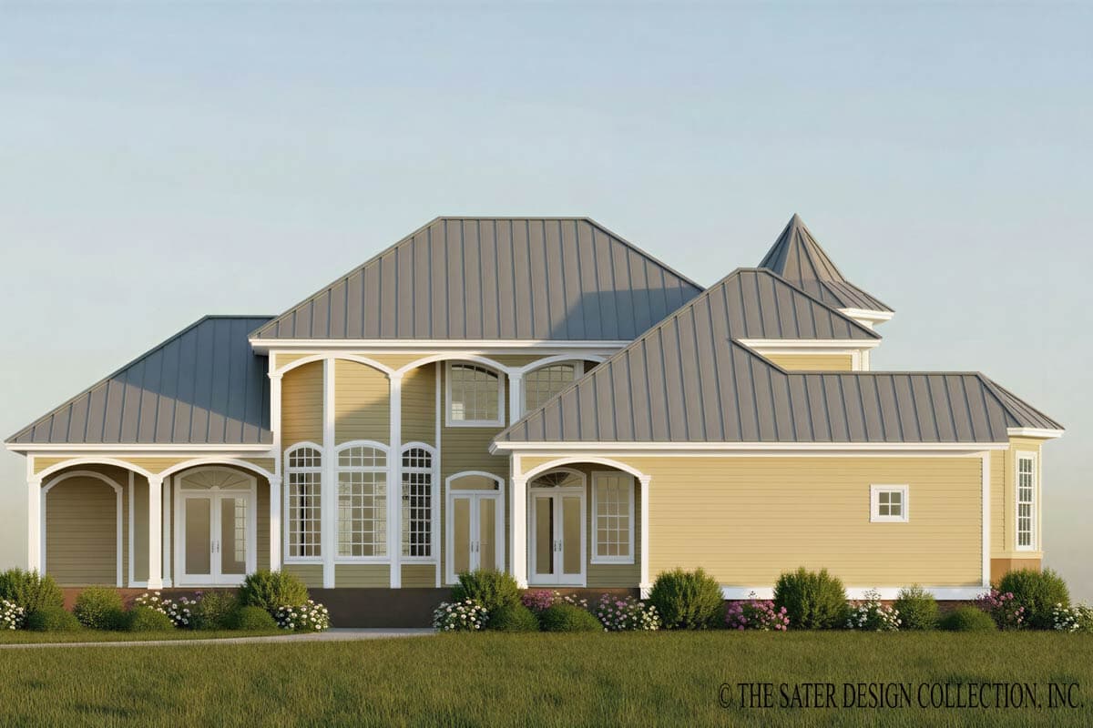 House plan exterior: Yellow siding, gray metal roof, arched window details, covered porch with columns, and a turretted roof section.