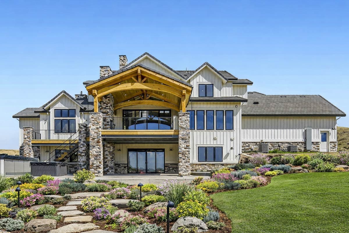 Modern Farmhouse house plan exterior with stone accents, large timber-framed covered deck, and multiple gables.