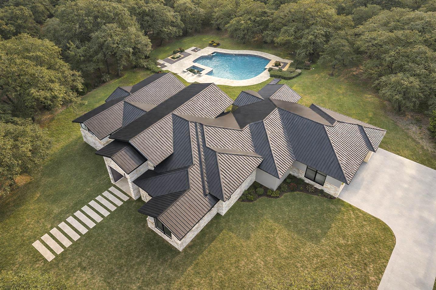House plan exterior with stone facade, multiple intersecting gables, and dark metal standing seam roof.