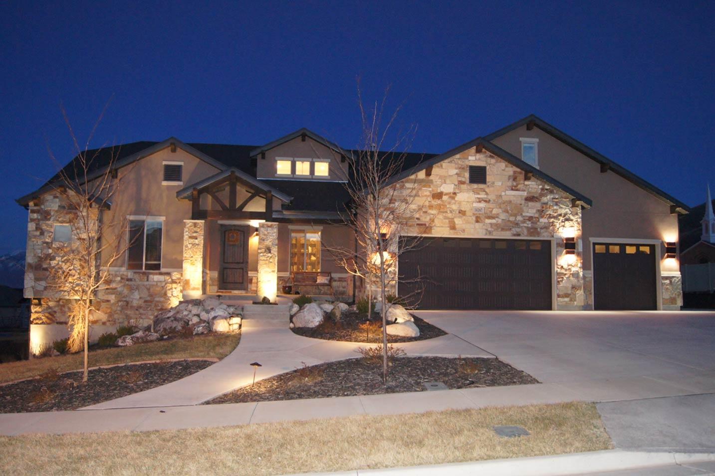 House plan exterior: two-story dwelling with stone accents, covered entry with timber beams, and a three-car garage.