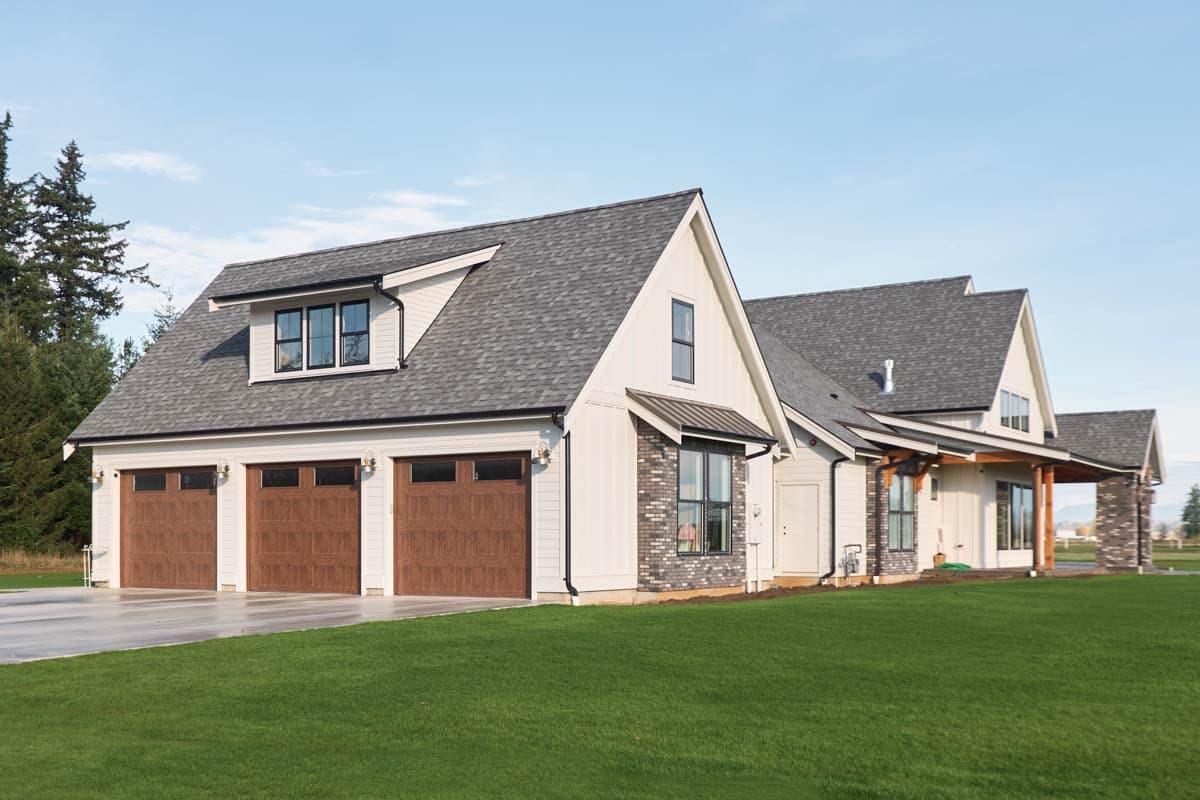 House plan exterior with three-car garage, dormer, gabled rooflines, and covered porch.