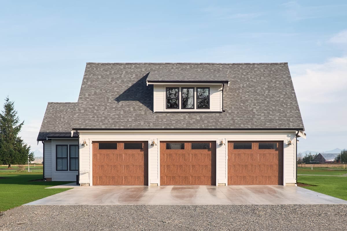 House plan exterior: A modern farmhouse style with a three-car garage, dormer, and side entrance.