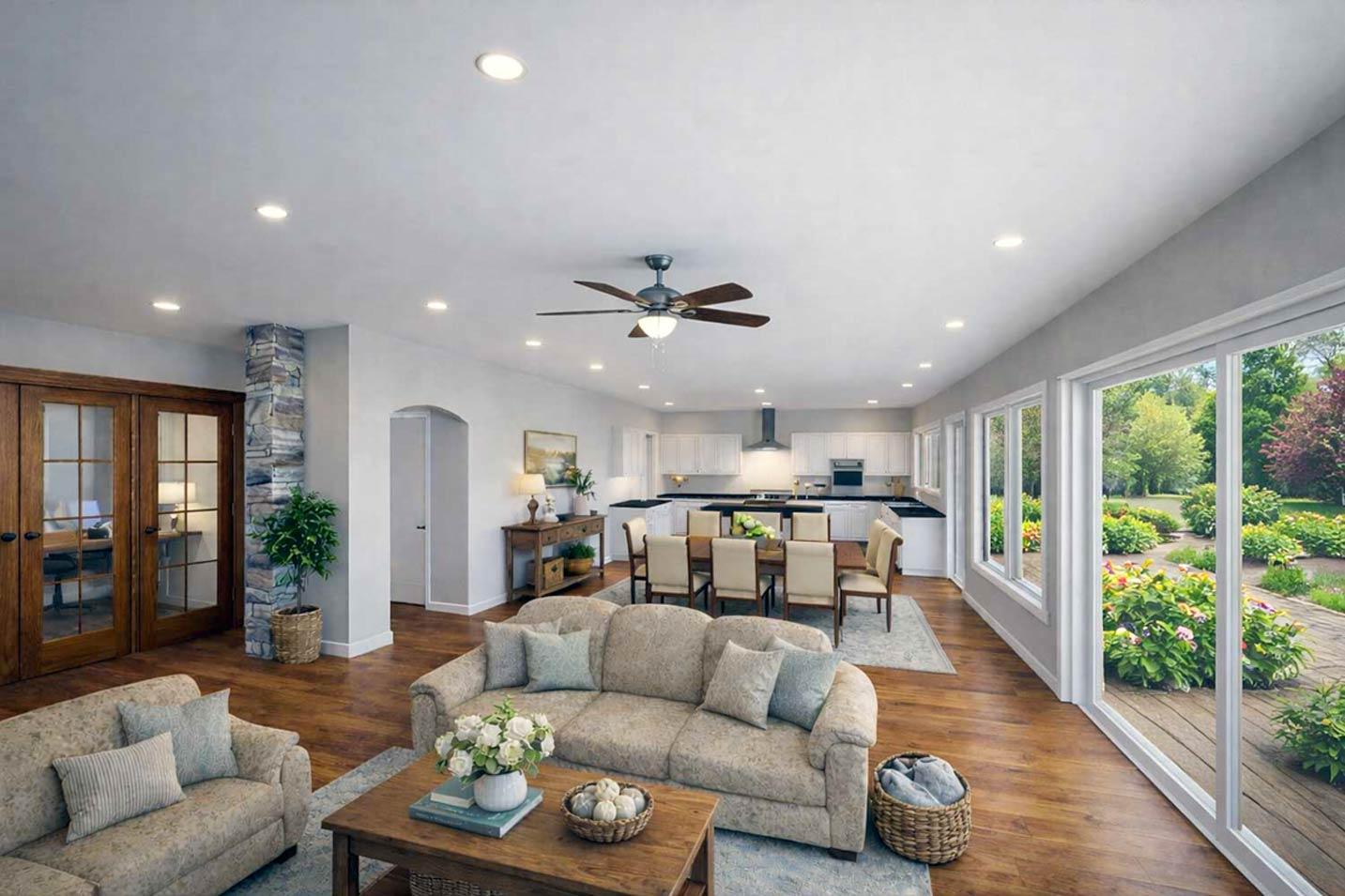Open concept living area with stone-clad column, dining area, white kitchen, and wall of windows overlooking gardens.