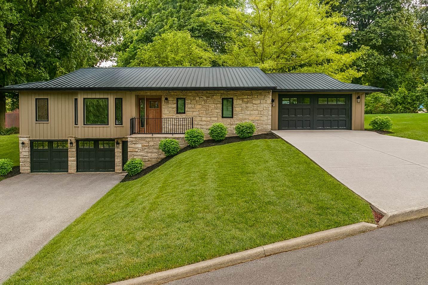 Modern house plan exterior with stone and tan siding, a metal roof, and three garage doors.