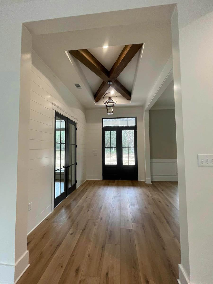 Interior view of entryway with wood plank flooring, shiplap accent wall, and decorative coffered ceiling with exposed beams.