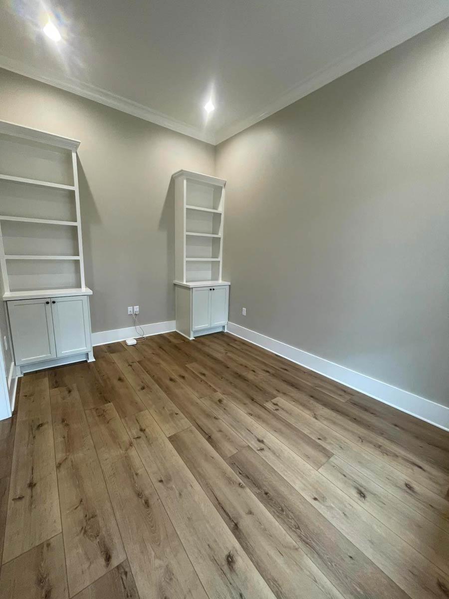 Interior view of a room with built-in white bookshelves on opposing walls and light wood-look flooring.