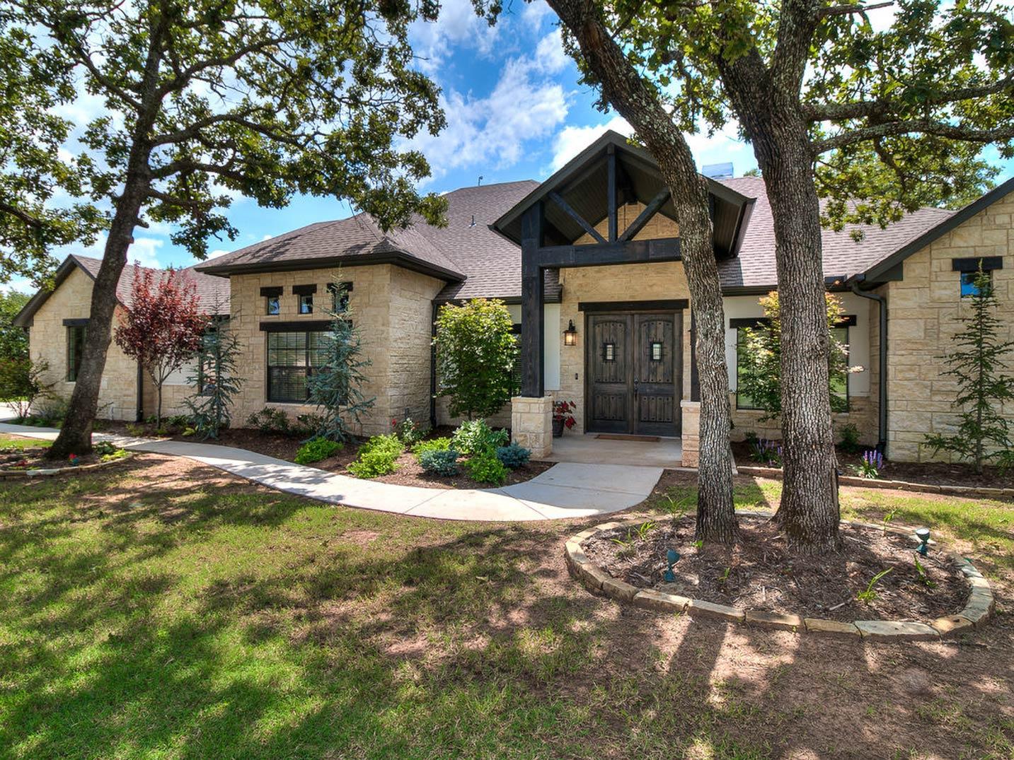 House plan exterior: One-story home with stone facade, prominent gabled entrance, and double entry doors.