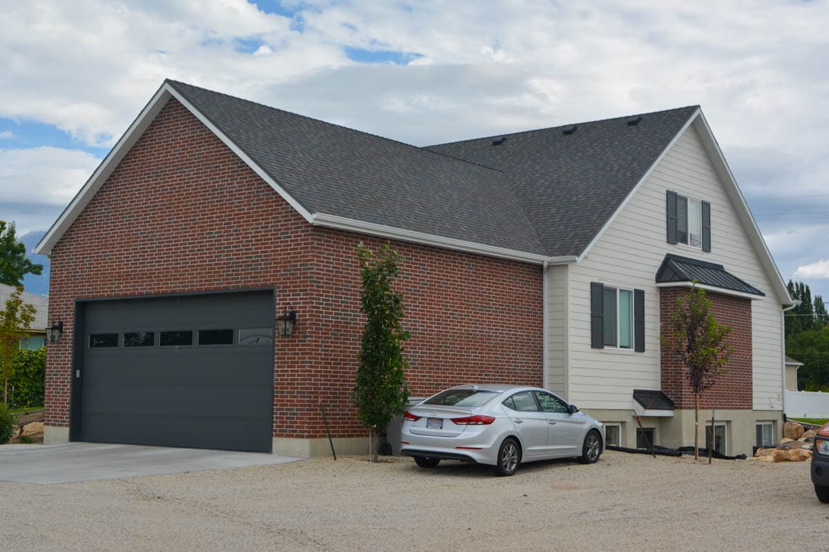 House plan exterior: Two-story residence with brick and vinyl siding, large garage door, and gabled rooflines.