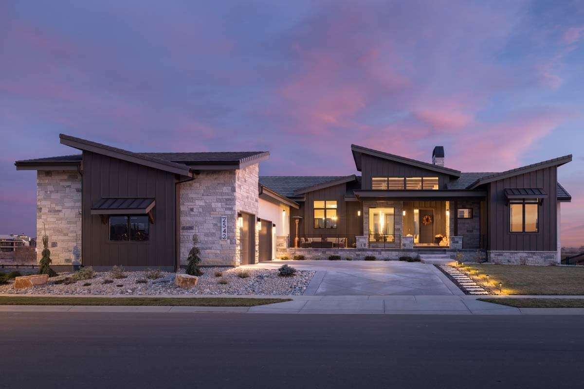 Modern house plan exterior with stone and dark wood siding, multiple gables, a covered entry, and attached garage.