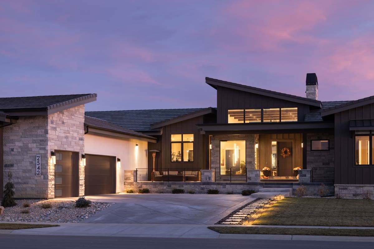 Modern house plan exterior with stone and wood siding, prominent gables, and a multi-level roofline.
