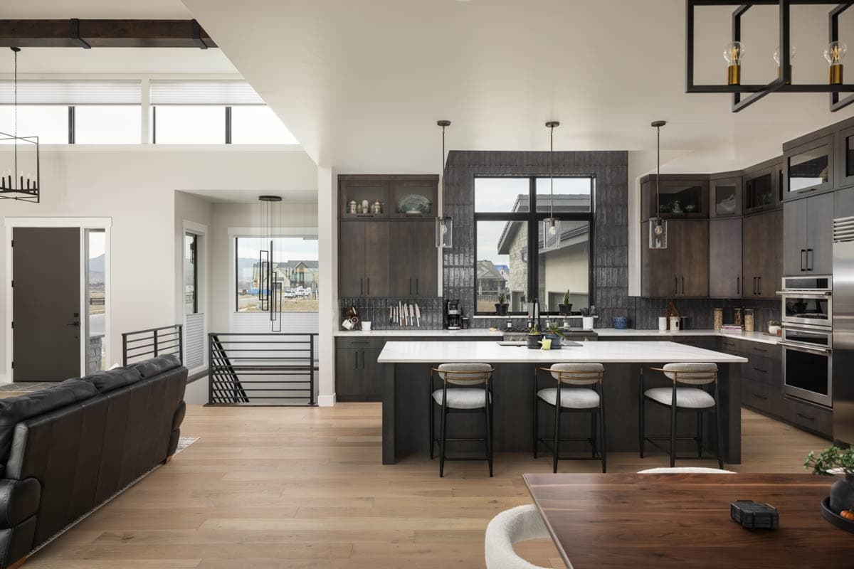 Open concept living area with dark wood cabinets, large island with seating, and modern lighting.